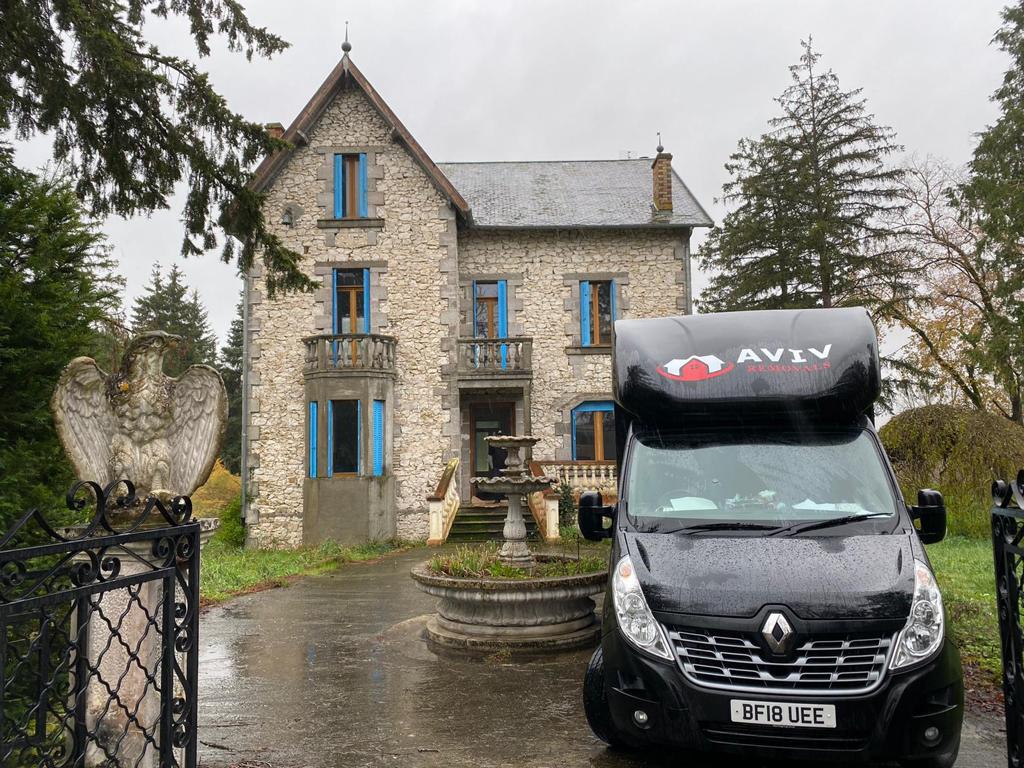 Aviv Removals van parked outside a large stone house with blue shutters before a residential move