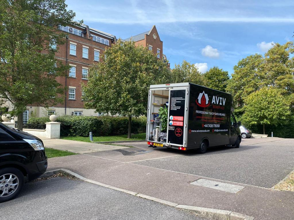 Aviv Removals van with rear doors open on a tree-lined residential street, ready for loading